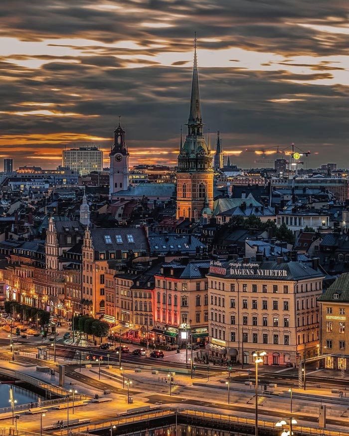 Evening cityscape of a European city with historic buildings and a dramatic sky, illustrating countries that sleep the most.