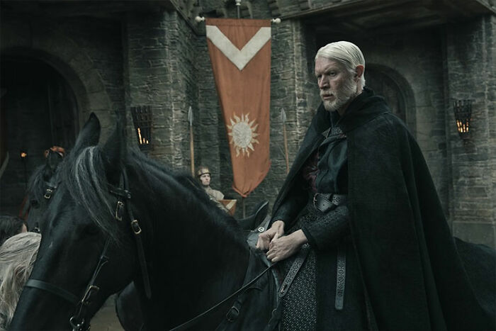 A Knight Of The Seven Kingdoms cast member in medieval attire on horseback inside a stone castle courtyard. A Knight Of The Seven Kingdoms cast member in medieval attire on horseback inside a stone castle courtyard.