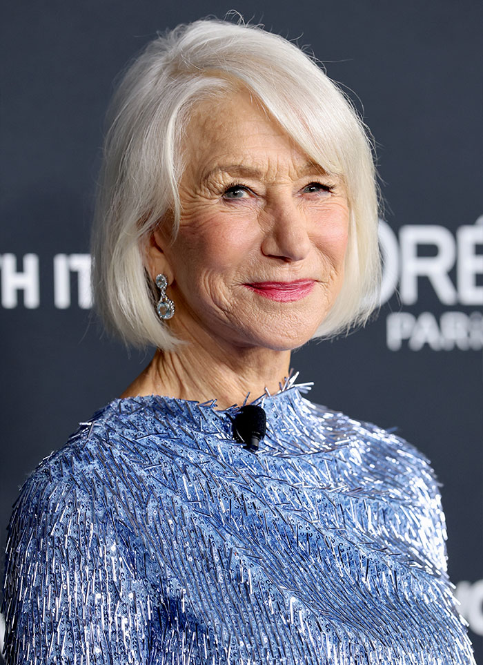Older woman with white hair wearing blue textured dress and earrings at event, representing female stars and childfree choices.