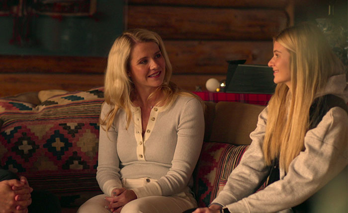 Two women having a conversation on a patterned couch in a cozy room, related to Elizabeth Smart Netflix documentary.