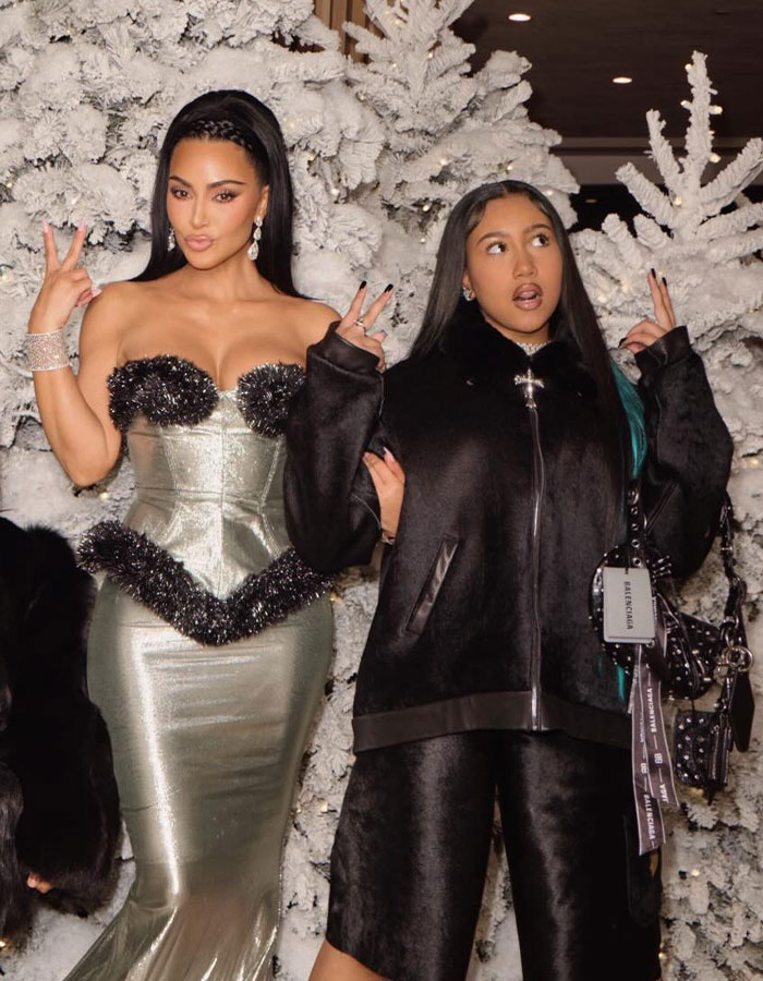 Kim Kardashian posing with a friend in front of white Christmas trees, linked to parenting controversy and viral livestream moment.