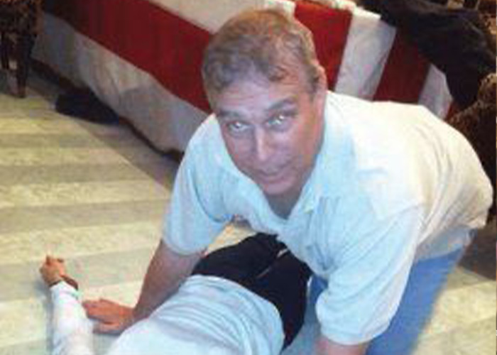 Prince Andrew leaning over a person lying on the floor, related to new disturbing images and emails controversy.