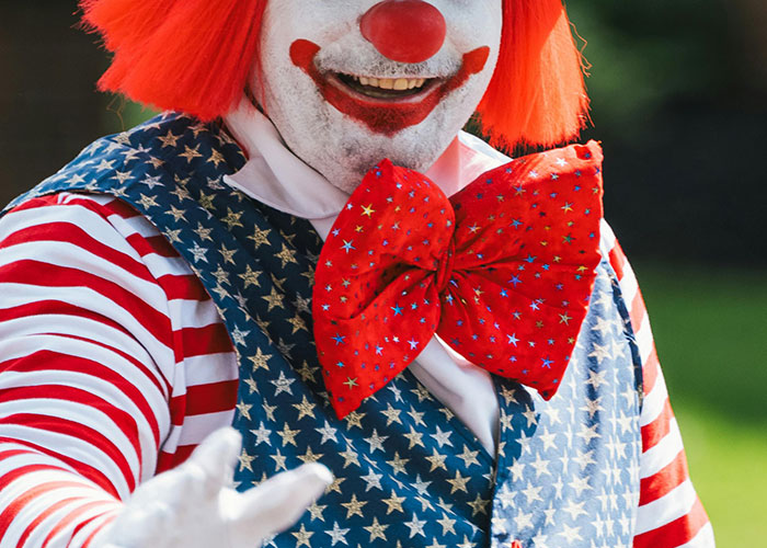Clown in patriotic star-spangled vest and oversized red bow tie, part of wacky stories shared by people for belief.