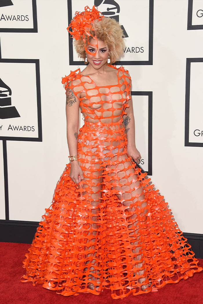 Woman in a bold orange cutout dress at the Grammys showcasing one of the wild Grammys looks on the red carpet.