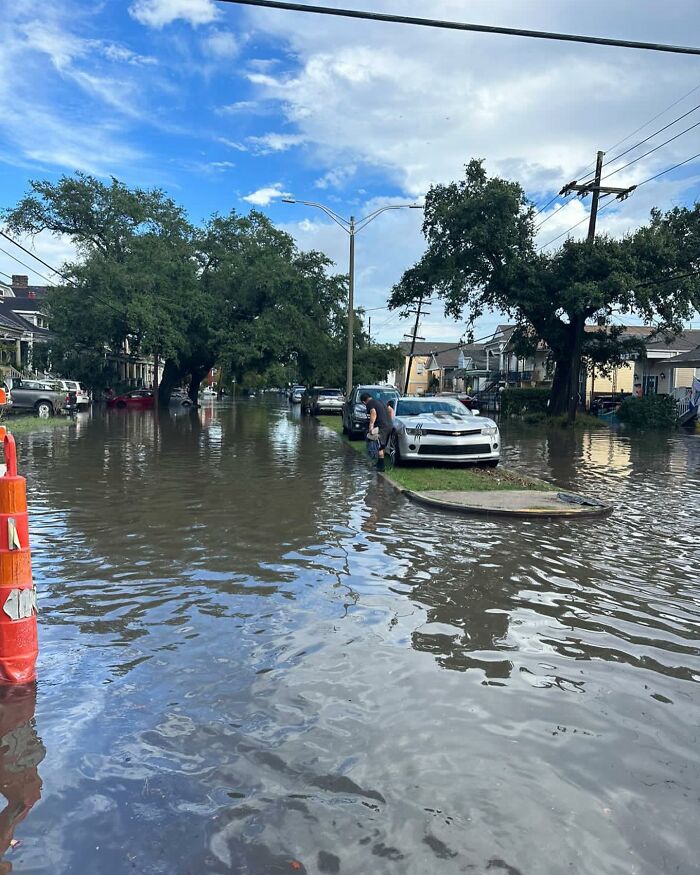 Flooded street with cars partially submerged and a person walking through water, capturing weirdest things found in the streets.