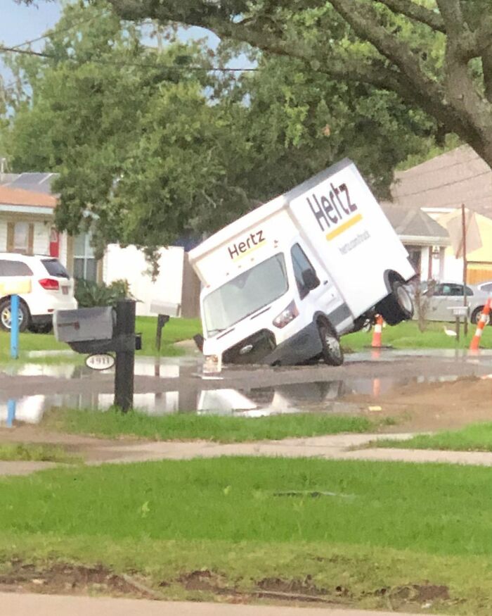 A rental truck stuck in a large pothole on a residential street, one of the weirdest things found in the streets.