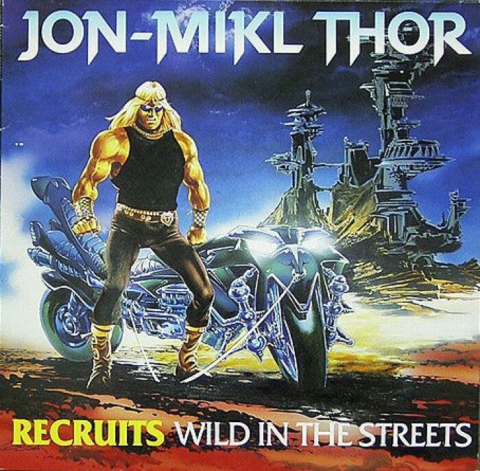 Hilariously bad album cover showing a muscular cartoon man with long blonde hair standing next to a futuristic motorcycle.