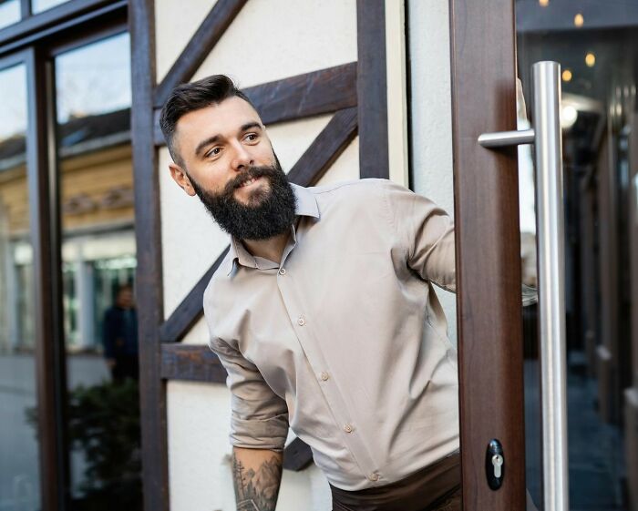 Man opening door cautiously, illustrating common safety measures women do to feel safer while living alone.