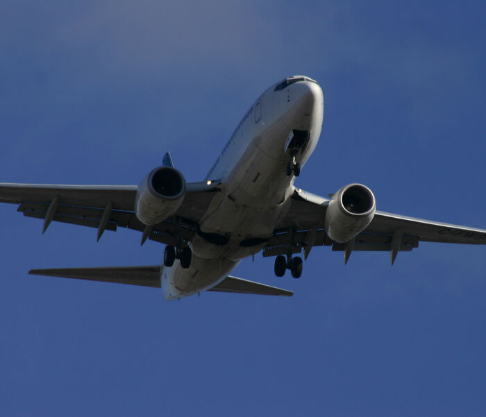 Underside of passenger jet approaching, illustrating sardine can seating on new planes