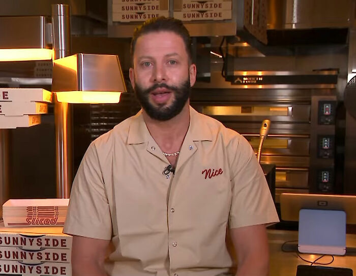 Pizzeria owner with beard in kitchen, known for his salty replies to harsh online reviews at Sunnyside Pizzeria.