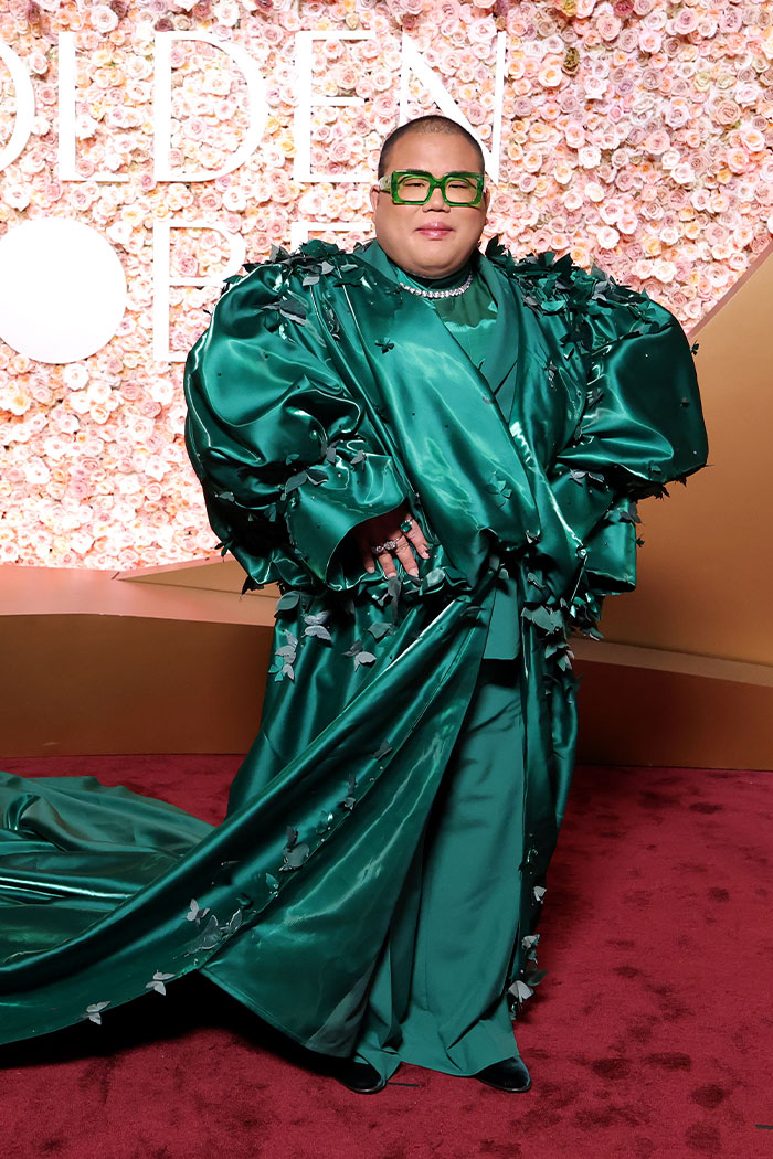 Person wearing oversized green satin gown with floral details and green glasses on the red carpet fashion disasters event