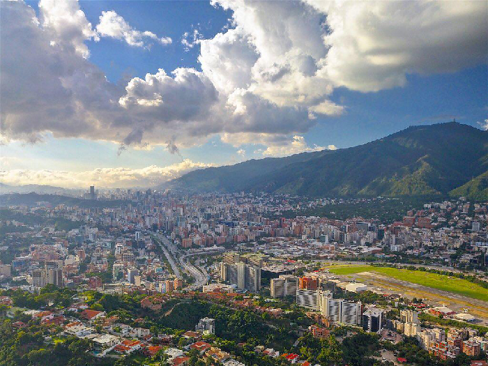 Most Stressful Countries skyline: sprawling city with mountains, an urban runway and dramatic clouds overhead.