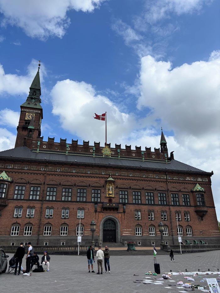 Historic brick building in Denmark with Danish flag flying, related to countries that sleep the most in OECD data.