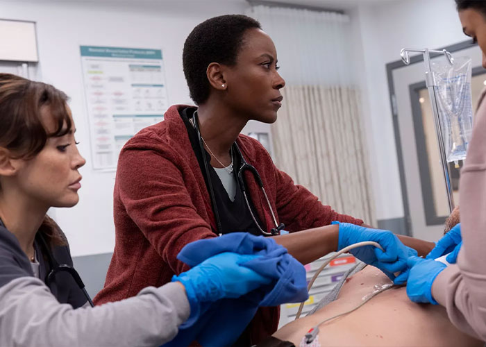 Dr. Heather Collins treating a patient in a hospital setting, central to The Pitt season 2 storyline.