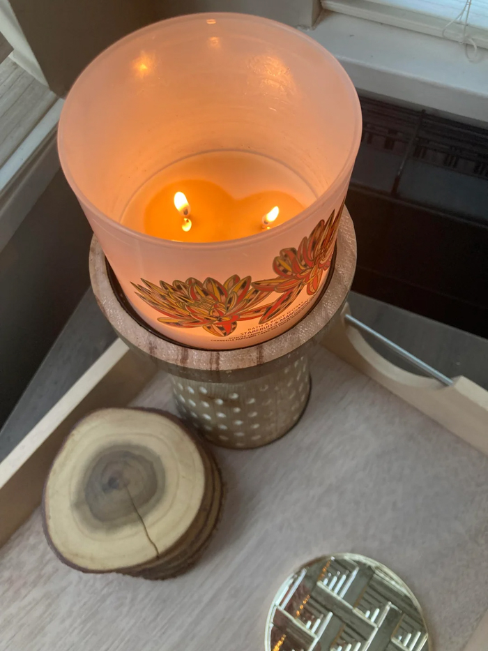 Candle burning on a wooden stand next to wood slice coasters, creating a cozy New Year’s resolutions atmosphere.