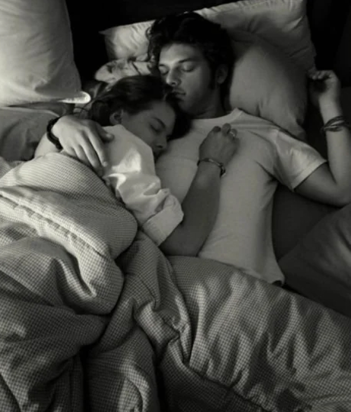 Couple sleeping closely in bed, illustrating the concept of women needing more sleep than men in a restful setting.