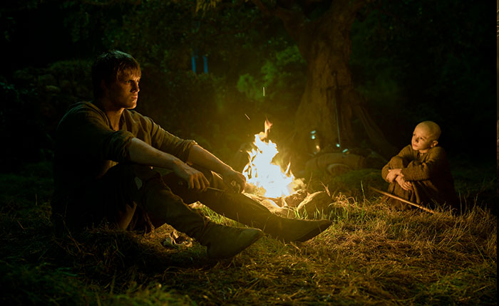 Peter Claffey sitting by a campfire in Knight of the Seven Kingdoms, fans reacting to critic's body comment in review.
