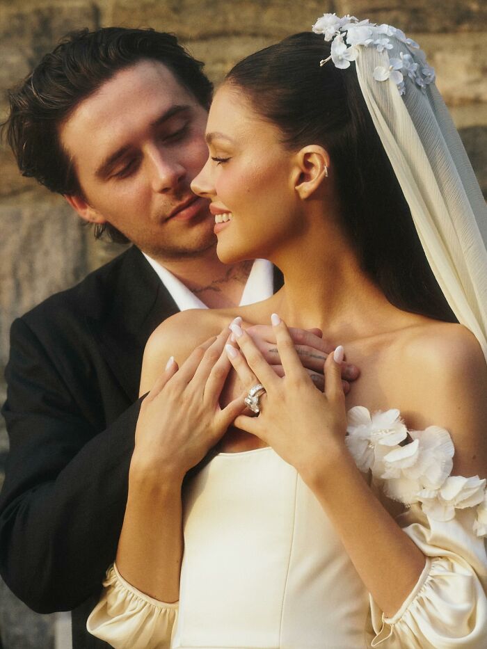 Brooklyn Beckham and bride in intimate moment, highlighting ring and wedding attire in soft natural light.