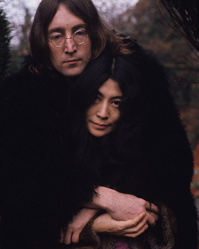 John Lennon and Yoko Ono embracing outdoors, representing hidden stories in famous songs and their impact on music history.