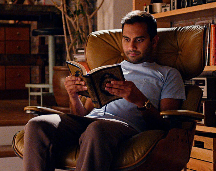 Man sitting in a leather chair reading a book, illustrating a quiet moment amid celebrity downfalls and public sympathy.