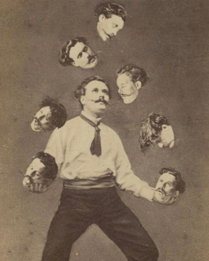 Man juggling seven floating heads in an old black and white photo with a strange and creepy vintage vibe.