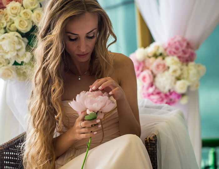Bride with long hair holding a soft pink flower, surrounded by wedding decor, representing fastest times couples said I do.