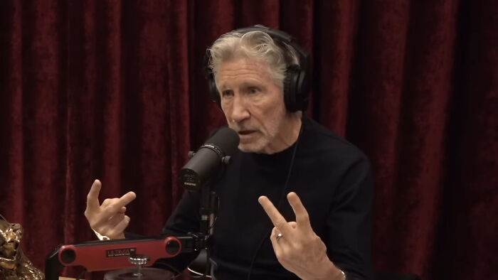 Older man wearing headphones speaking into a microphone, sharing stories about people meeting their idols in real life.