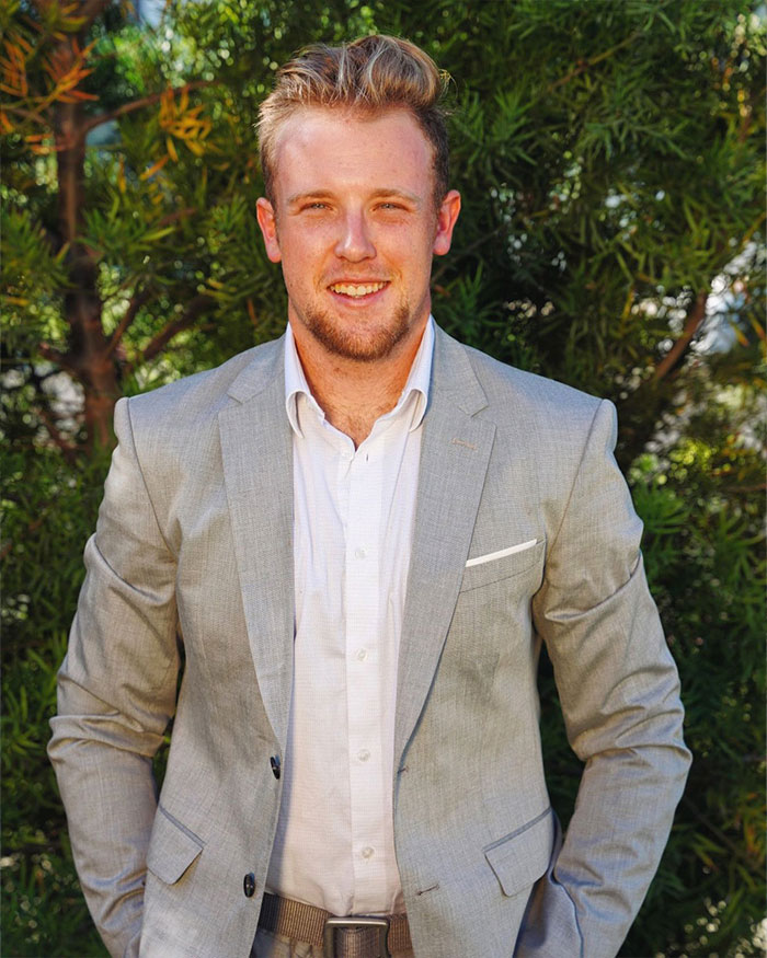 Young man in gray suit smiling outdoors, accompanying Disney World news article