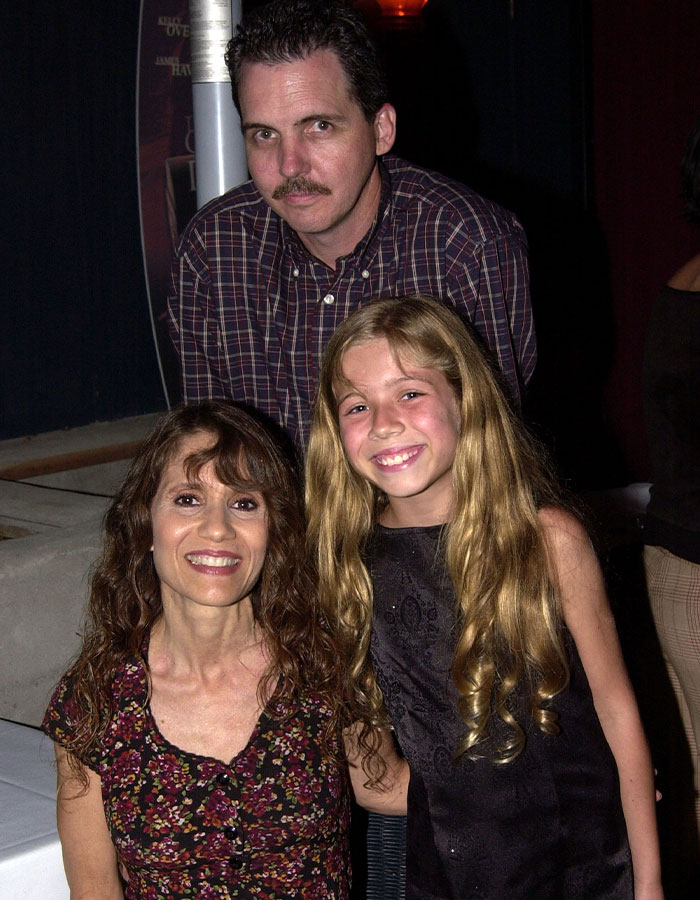 Man with mustache standing behind smiling woman and young girl, representing twisted addictive relationship keywords.