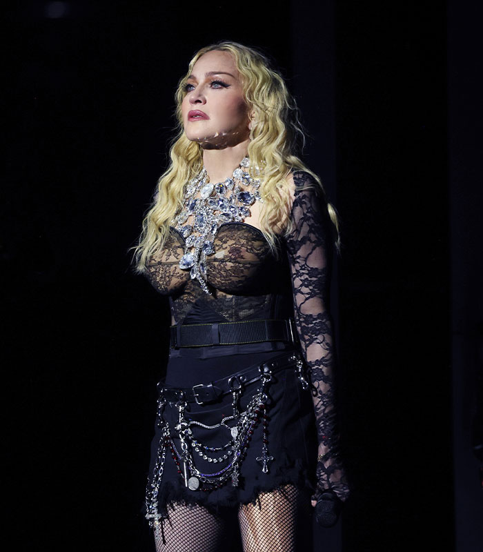 Madonna performing in a black lace outfit with elaborate jewelry during a controversial Ariana Grande fan backlash event.