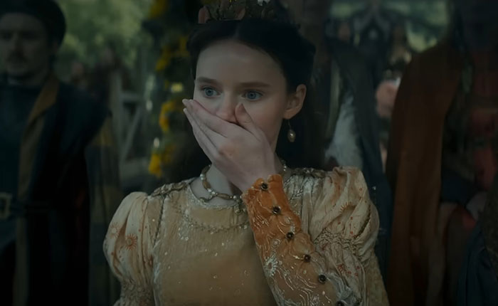 A shocked woman in medieval attire reacts amid fans divided over A Knight of the Seven Kingdoms Rotten Tomatoes rating.
