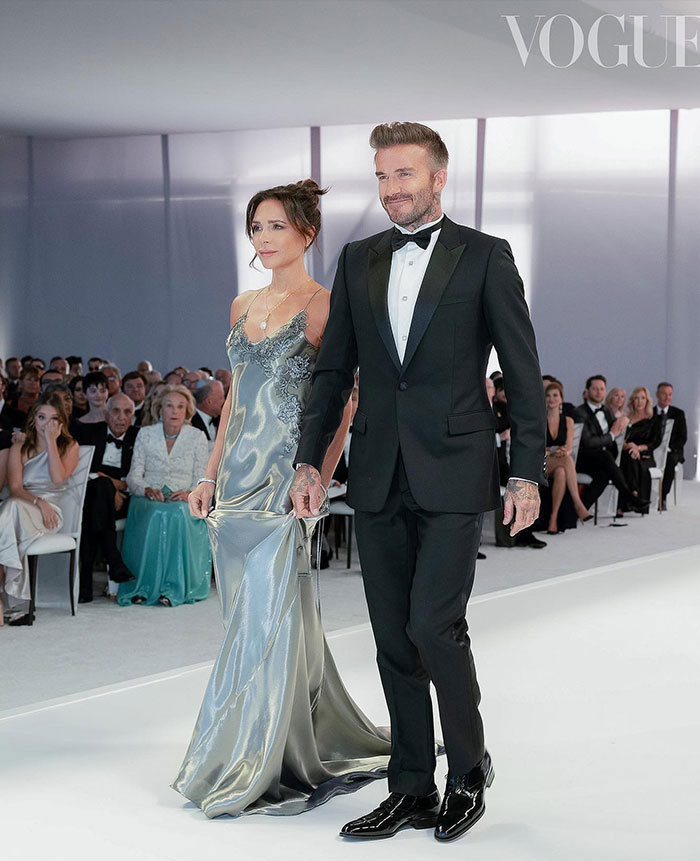 Couple walking on runway at formal event, with audience seated, related to DJ at Brooklyn Beckham wedding dance accusations.