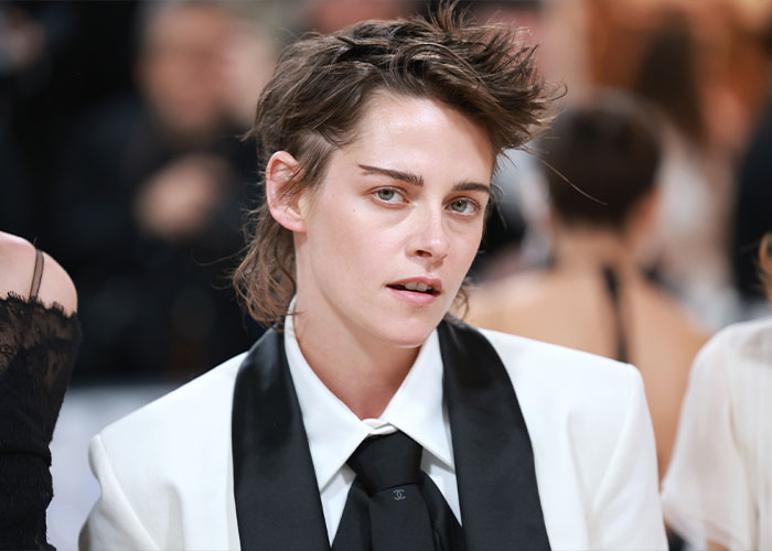 Kristen Stewart wearing a white suit and black tie, hinting at a deeper reason behind her possible exit from the US.