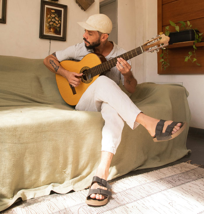 Man sitting on a sofa playing guitar, illustrating moments that made sense once the cheating came out, highlighting the phone.