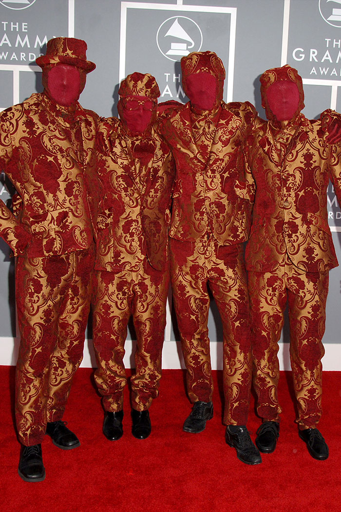 Group of four people wearing bold patterned suits and red face coverings at the Grammys with wild Grammys looks style.