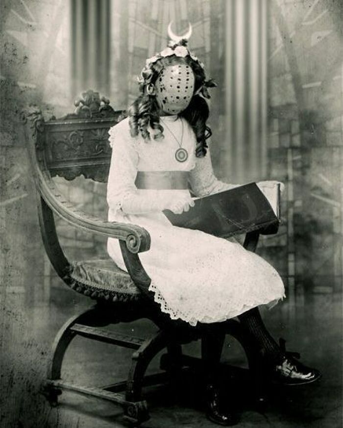 Vintage black and white photo of a girl in a lace dress with a creepy mask sitting on an ornate wooden chair.