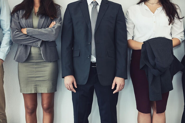 Group of professionals standing in formal business attire illustrating pointless and infuriating office rules.