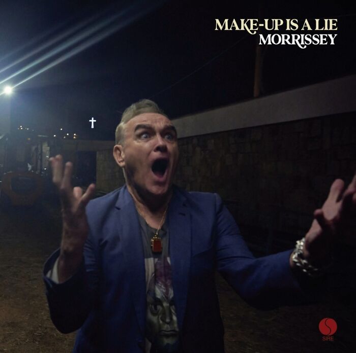 Man in blue jacket with shocked expression posing outdoors at night on a hilariously bad album cover by Morrissey.