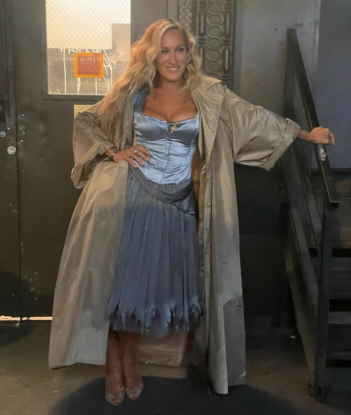 Woman in a blue satin dress and beige coat posing indoors, related to Chris Noth breaking silence after fan backlash.