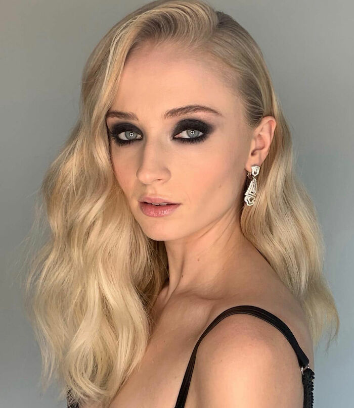 Sophie Turner with smokey eye makeup and wavy blonde hair, showcasing her Lara Croft transformation for Tomb Raider.