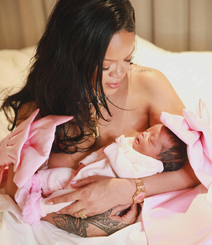 Woman cradling newborn in pink outfit on bed, linked to distorted lingerie photos controversy