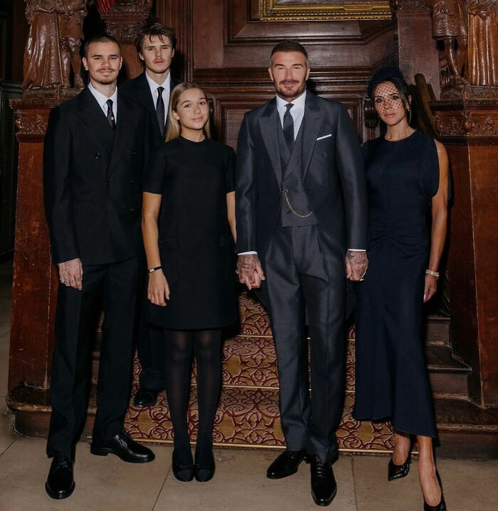 Beckham family dressed formally standing indoors, with Cruz Beckham referencing Brooklyn's claim about Victoria's wedding dance.