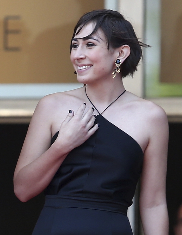 Victoria, Tommy Lee Jones&rsquo; daughter, smiling and wearing a black halter dress with statement earrings at a public event.