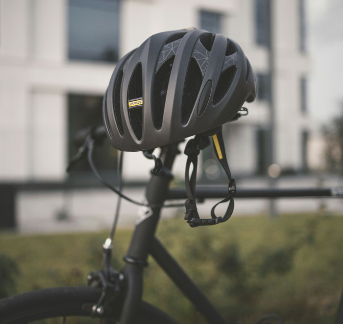 Black bike helmet hung on a bicycle handlebar in front of a building, weird friends or family