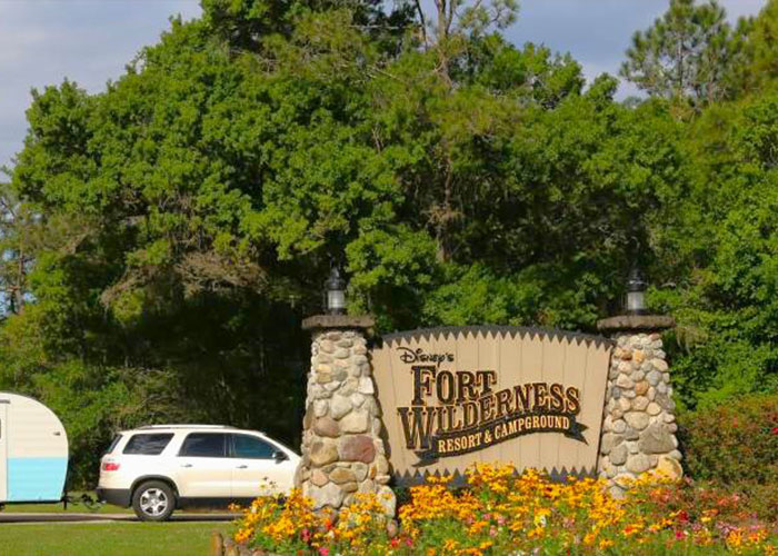 Disney World Fort Wilderness sign with flowers and a parked SUV at the resort entrance