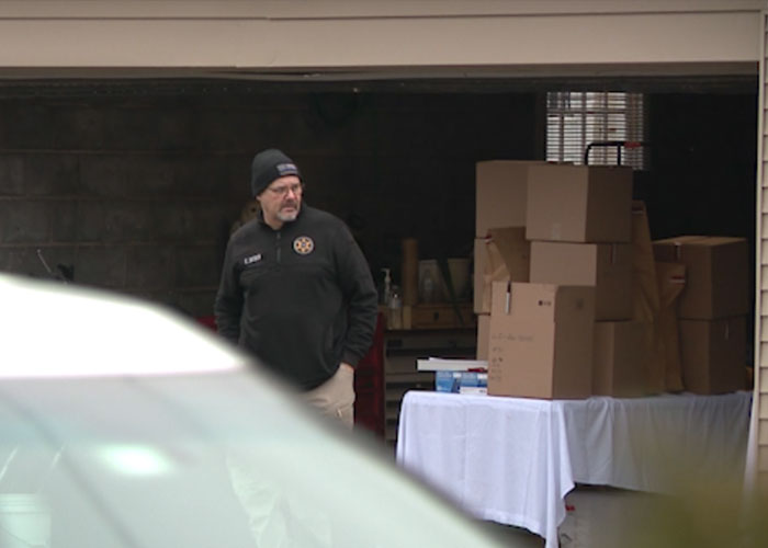 Man in a black jacket and beanie standing near a garage with stacked boxes related to a skull discovery investigation. Man in a black jacket and beanie standing near a garage with stacked boxes related to a skull discovery investigation.