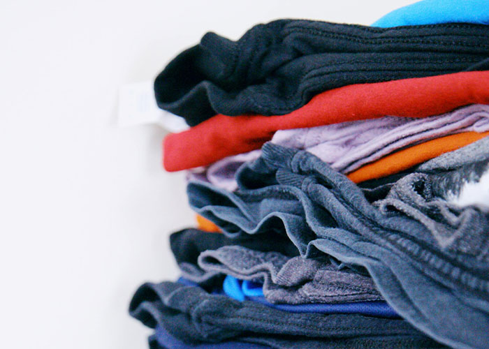 Folded clothes in various colors stacked in a pile, illustrating comfort and sensory preferences of neurodivergent people.