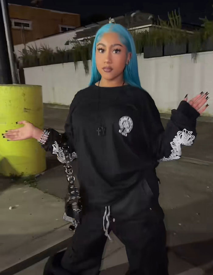 Young woman with blue hair in black outfit posing outdoors at night, reflecting the vibe of super cringe livestream moments viral online.