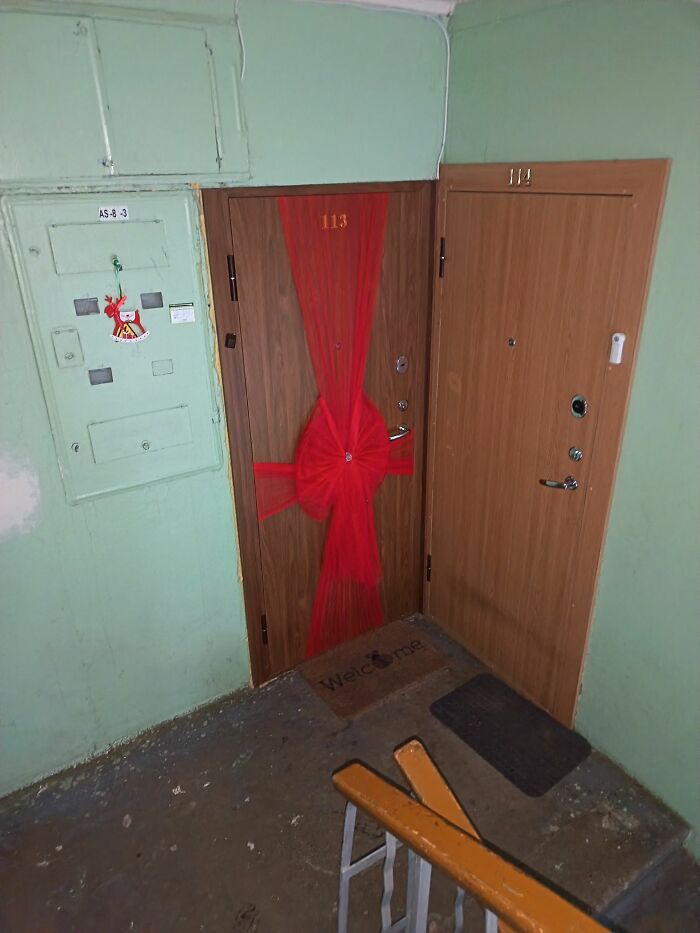 Apartment door decorated with a large red bow in a sad Lithuanian apartment building for Christmas.