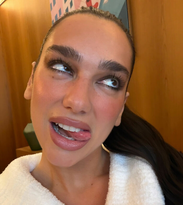 Dua Lipa making a playful face indoors, reacting with surprise to a fan&rsquo;s filter during a selfie moment.